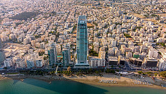 Luftaufnahme von dem luxuriösen Wohntower ONE mit der Stadt Limassol im Hintergrund.