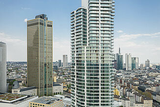 Fassade des Grand Tower mit der Skyline Frankfurts im Hintergrund.