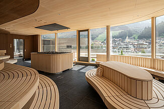 Moderne Saunawelt mit großer Glasfront und Blick in die Berge in der Silvretta Therme in Ischgl.