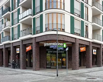 Der Eingang eines Mixed-Use Gebäudes mit verschiedenen Geschäften und einem Supermarkt.