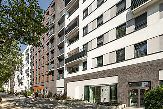 Straßenansicht mit Tiefgarageneinfahrt und Eingang zu den Wohnbereichen in dem Mixed-Use Quartier Alea in Frankfurt.