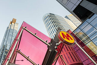 Rotes Glasdach eines Metro Eingangs inmitten der Skyline von  Warschau.