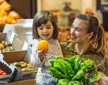 Eine Frau und ein Kind kaufen im Supermarkt Obst und Gemüse.