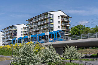 Eisenbahnbrücke mit Zug und zwei Gebäude im Hintergrund