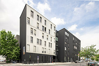 Außenansicht von der Straße der schwarz-weißen Fassade mit Fenstern des Büro- und Geschäftsgebäudes Pôle PIXEL in Frankreich.