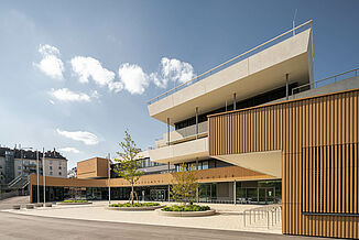 Front view of the Aaron Mencer Campus in Vienna with wooden façade.