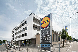 Mixed-Use Gebäude mit einem Lidl, Wohnungen und einem Spielplatz.