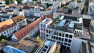 Eine Luftaufnahme eines sanierten Stadtviertels in Berlin mit begrünten Dachterrassen und nachhaltiger Dacharchitektur.