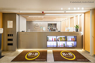 Rezeption im B&B Hotel Hannover als Teil des Brownfield Stadtteilzentrums mit nachhaltigem Bauen und ressourcenschonenden Lösungen.