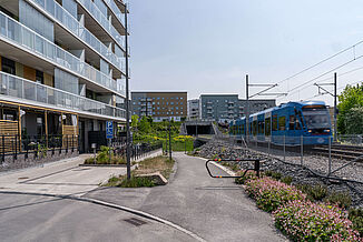 Zug passiert Wohnkomplex mit Balkonen