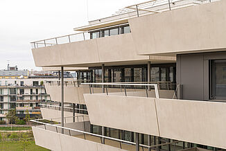 Seitlicher Blick auf ein Gebäudeteil mit umlaufenden Terrassen des Aaron Mencer Campus in Wien.