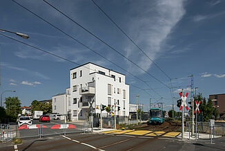 Mehrfamilien-Wohnhaus in Oberursel mit vorbeifahrender Straßenbahn.