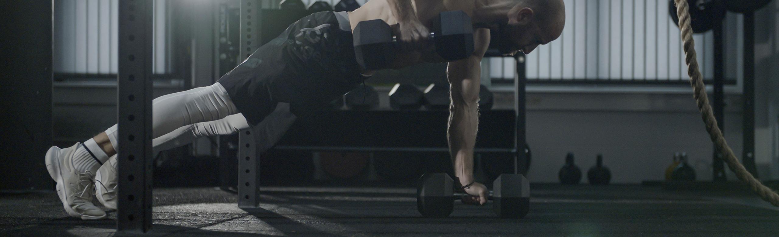 A man trains with dumbbells on a REGUPOL fitness floor.